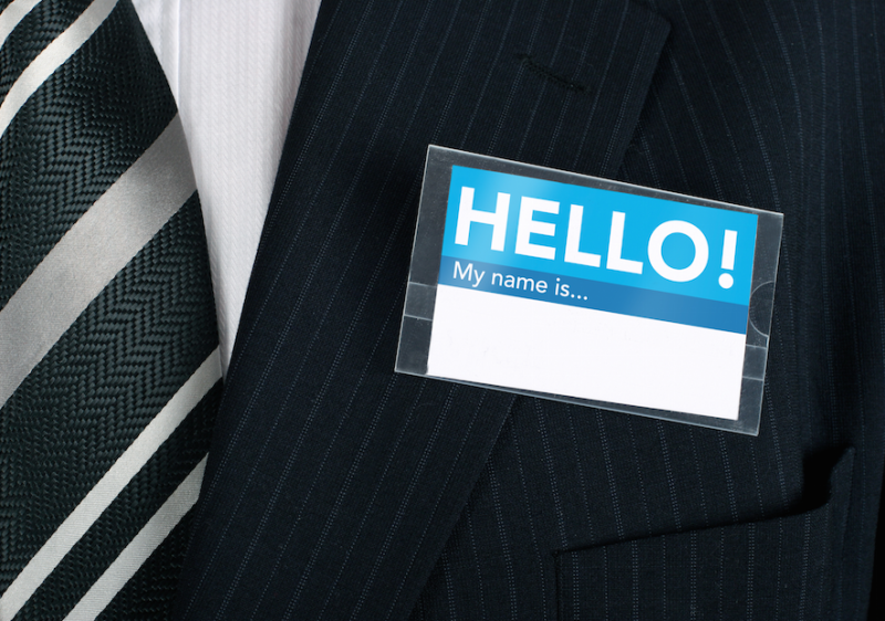 Man in suit with 'HELLO My name is' tag